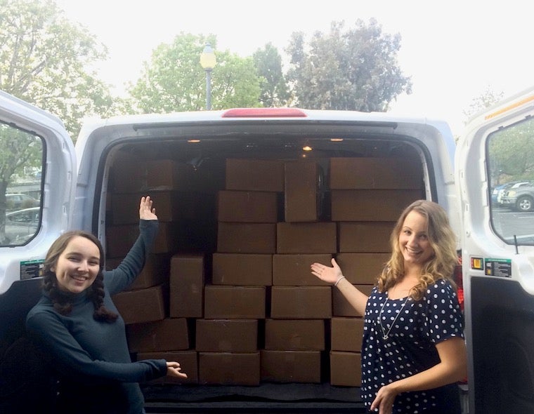 Kira and Jenny in front a truck full of boxes